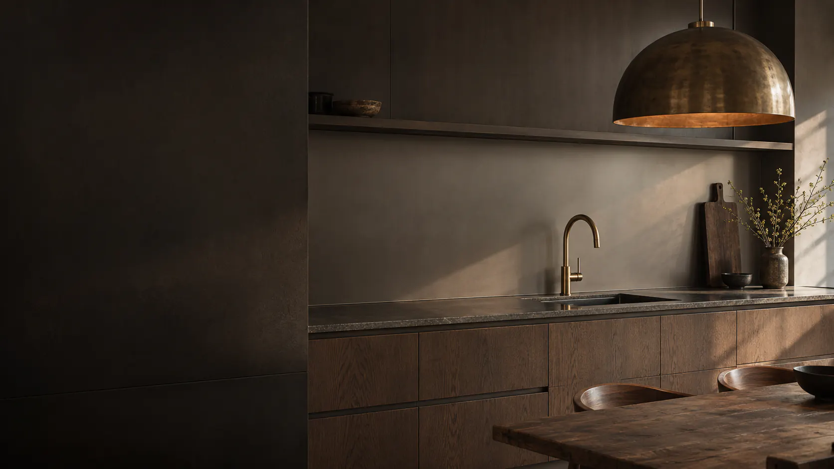 Donkere keuken met een warme achterwand, messing kraan en een koperen hanglamp boven het werkblad