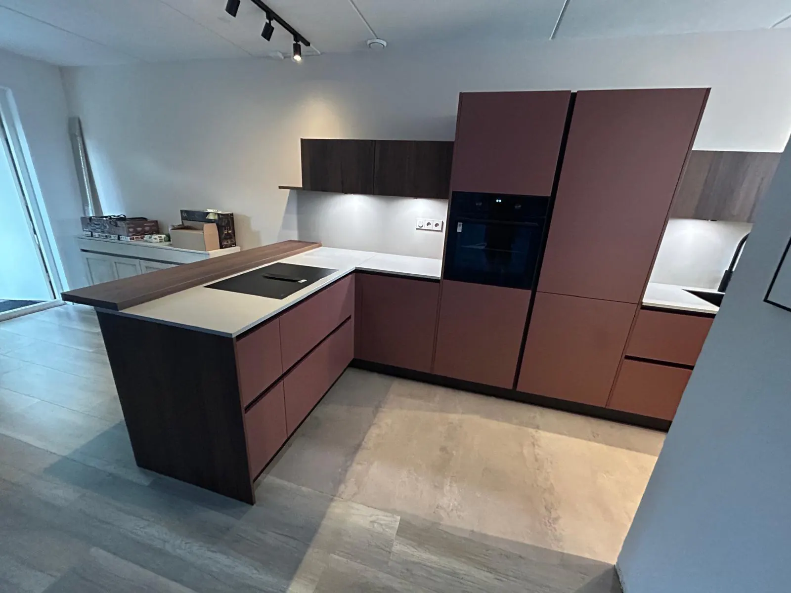 Keuken met roodbruine kastfronten, een licht werkblad en een eiland met houten bar