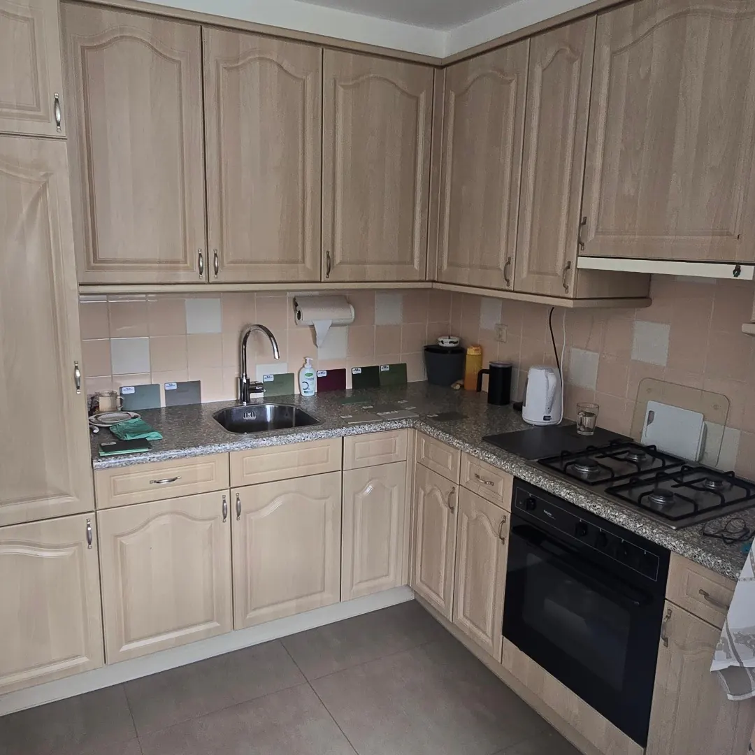Keuken vóór de vernieuwing, met lichte houtkleurige kastfronten en een betegelde achterwand